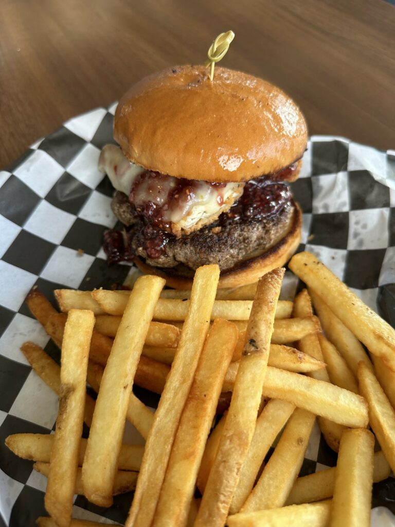 Gourmet cheeseburger with fries on checkered paper.