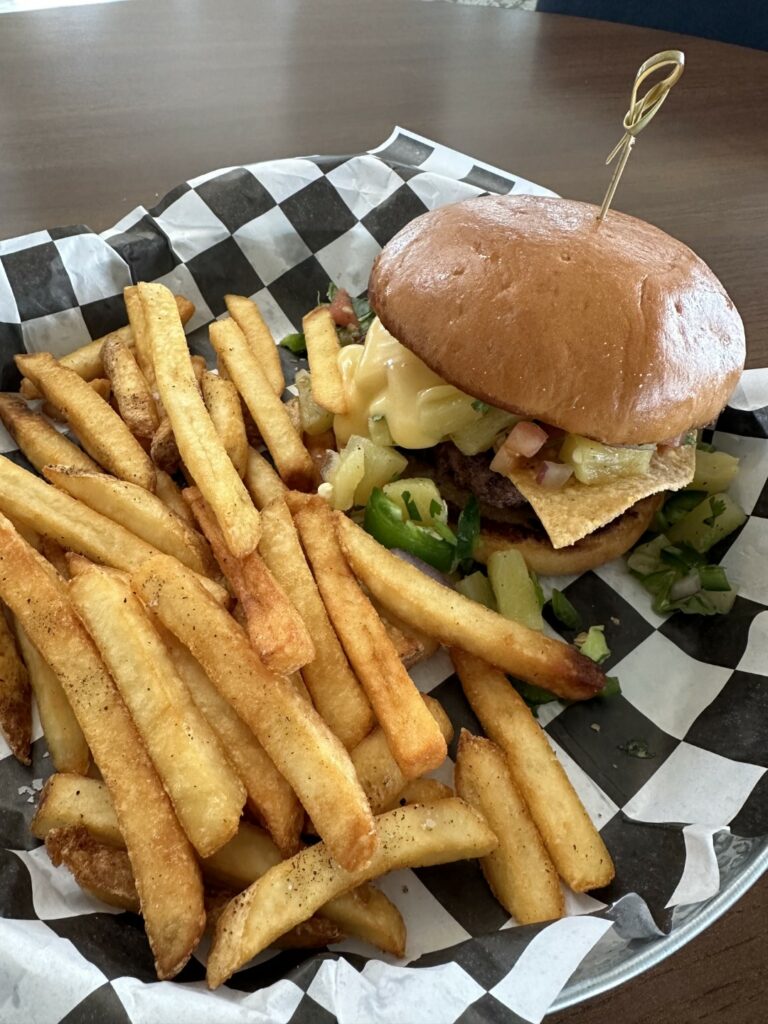 Cheeseburger with seasoned fries on checkered paper.