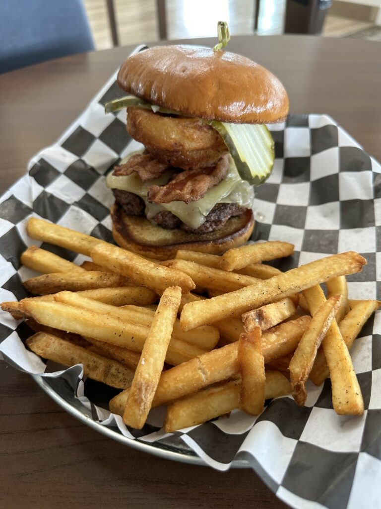 Loaded cheeseburger with fries on checkered paper.