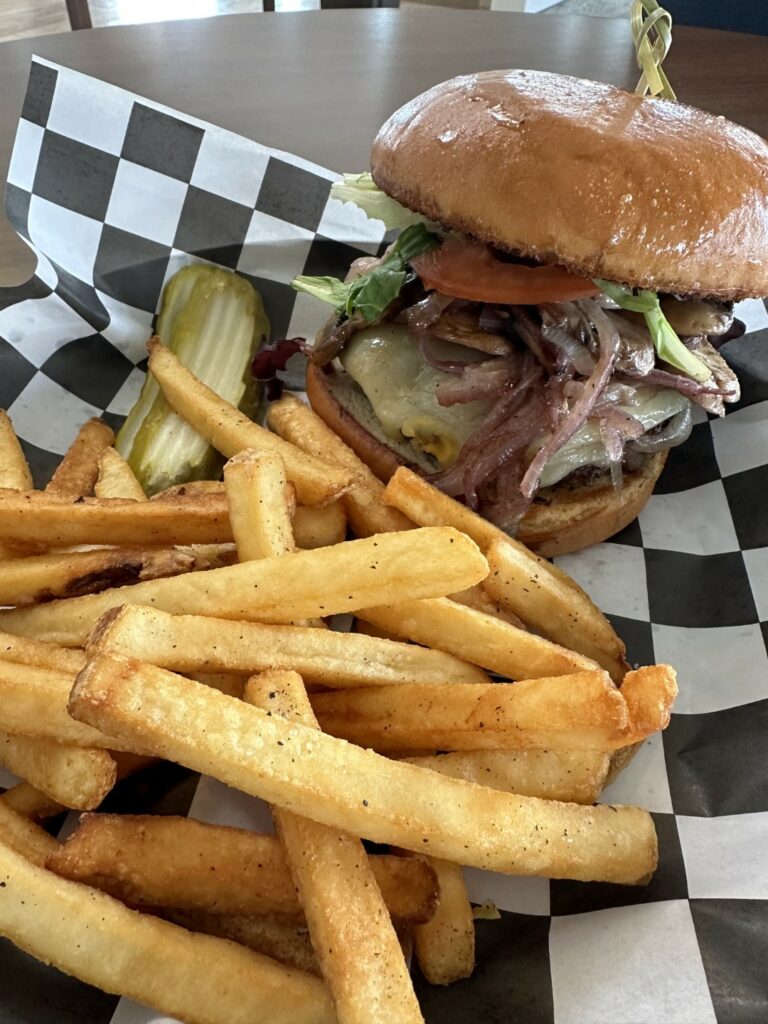 Juicy burger with fries on checkered paper.