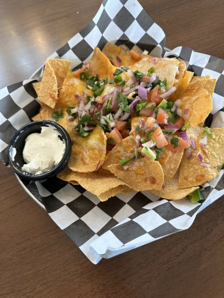 Cheese nachos with pico de gallo and sour cream.