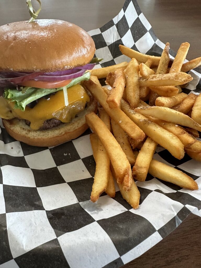 Cheeseburger with lettuce and fries on checkered paper