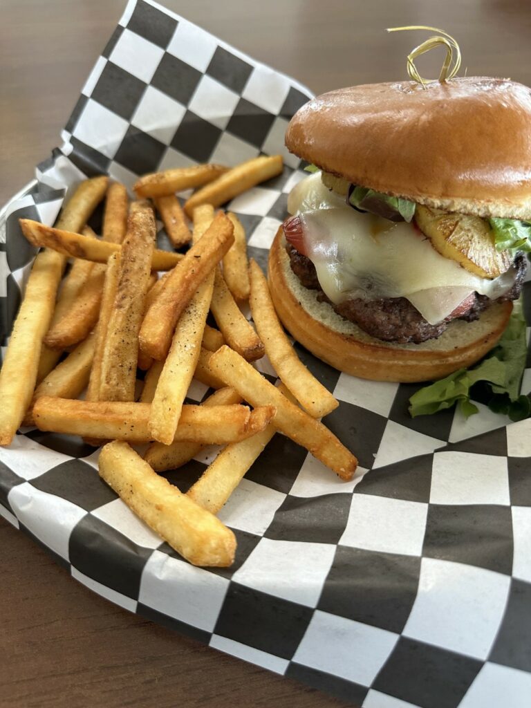 Cheeseburger with fries on checkered paper.